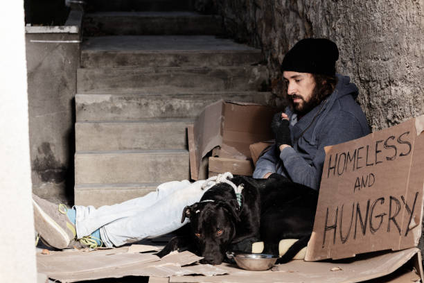 istock Houseless man sitting with his dog on backstreet 1094446884