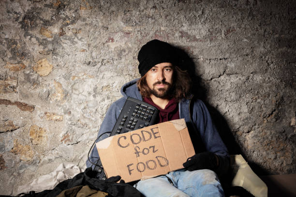 istock Man sits on floor with keyboard and cardboard sign 1094446912