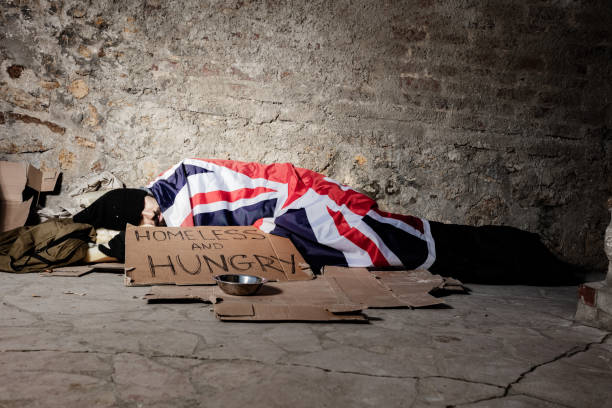Man sleeping on street under Great Britain flag Homeless man begging for alms, sleeping on the street covered with Great Britain flag beg alms stock pictures, royalty-free photos & images