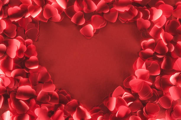 top view of beautiful heart shaped frame from decorative petals on red background