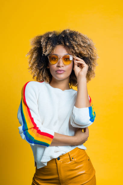 confident, beautiful afro girl against yellow background - cool glasses sunglasses fashion imagens e fotografias de stock