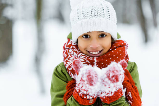 cute african american child showing white snow an smiling at camera in winter forest cute african american child showing white snow an smiling at camera in winter forest children in winter stock pictures, royalty-free photos & images
