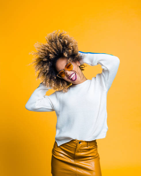 emozionata giovane donna afro che balla su sfondo giallo - alternative enregy foto e immagini stock