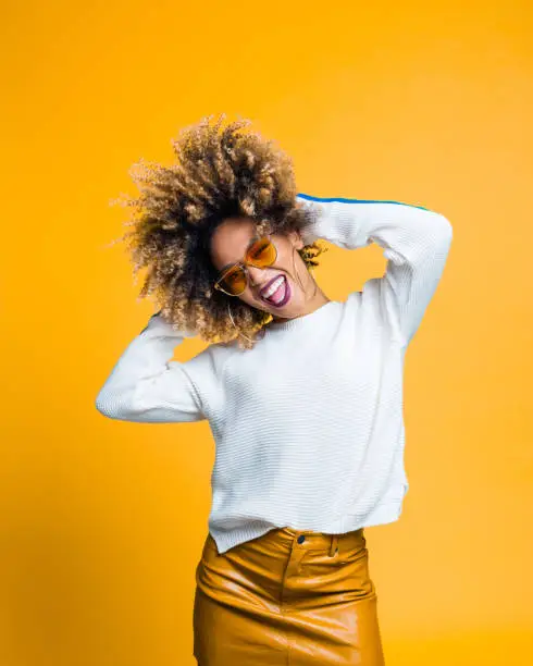 Photo of Excited afro young woman dancing against yellow background