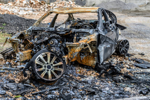 Burned and completely destroyed car left on the side of the road after an accident.