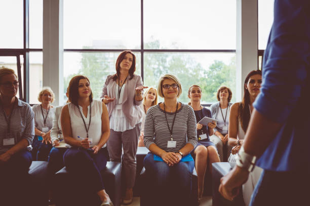 Businesswoman asking question during seminar Businesswoman raising a question to the speaker during a training. Woman asking question during seminar. woman press conference stock pictures, royalty-free photos & images