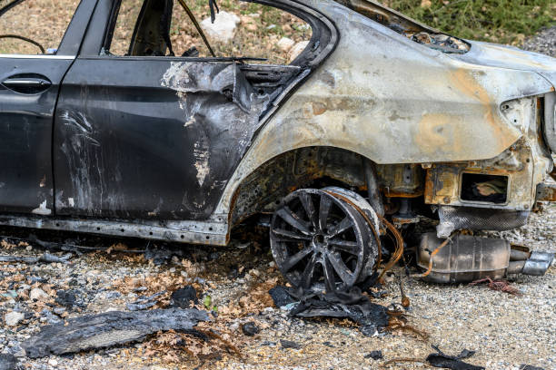 Wrecked and burned car completely covered in rust and ashes left on the side of the road after an accident.