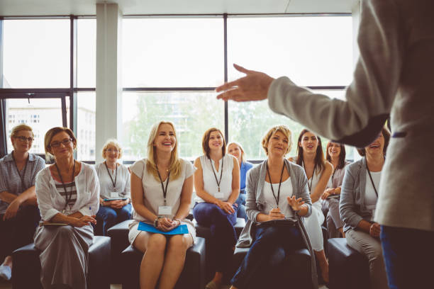 Skill development training for women Group of business women smiling and listening to the speaker during seminar. Women attending a skill development training in conference hall. woman press conference stock pictures, royalty-free photos & images