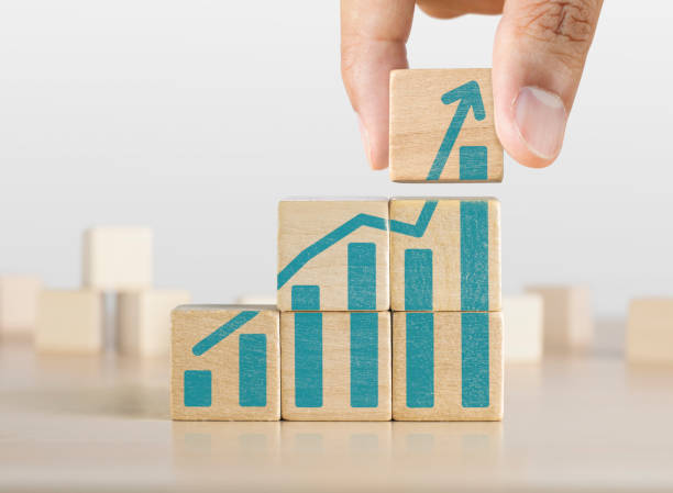 Business growth, progress or success concept. Wooden blocks with a growing bar chart graphic arranged in stair shape and a man is holding the top one. stock photo