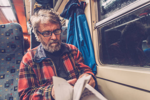 Hipster man sitting on a bus in the city, travelling to work and reading newspapers.