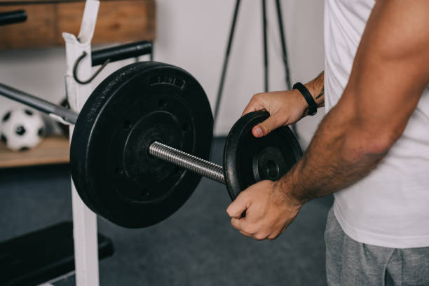 istock cropped view of man putting heavy disk on barbell 1094469206