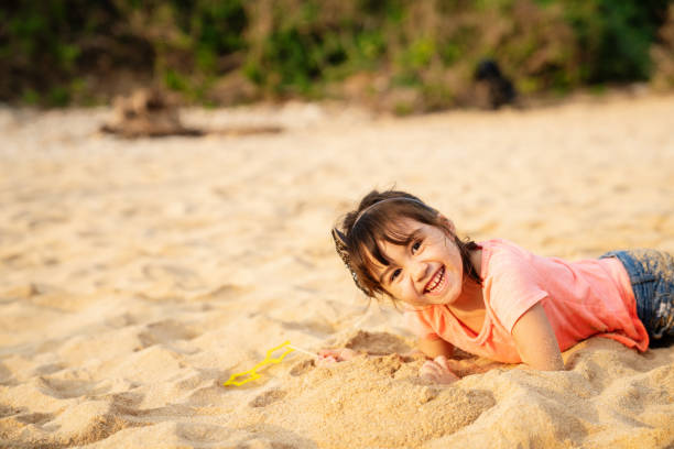 Young girl playing in the sand on a beach while on vacation