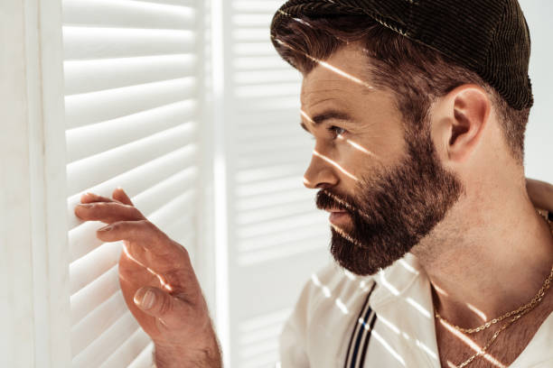 istock side view of handsome bearded man in cap looking through white room divider 1094469830