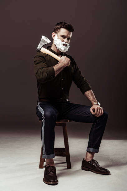 istock handsome bearded man sitting on chair and holding ax 1094470246