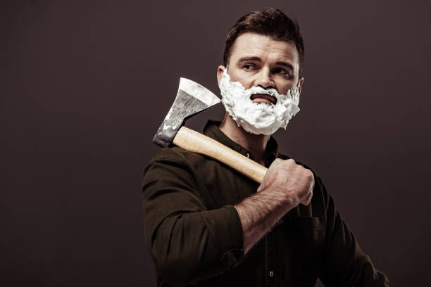 istock handsome bearded man with shaving foam on face holding ax isolated on brown 1094470258