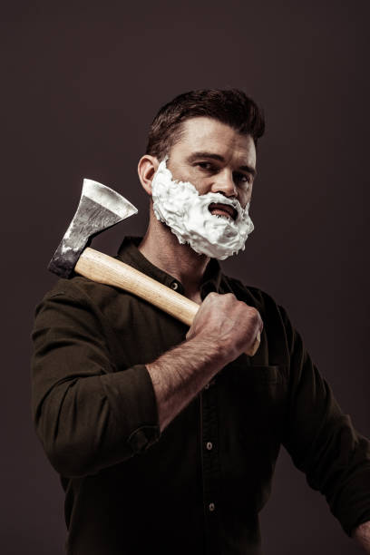 istock handsome bearded man in brown shirt holding ax while looking at camera isolated on brown 1094470304