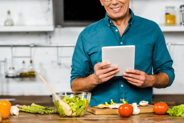 istock cropped image of smiling mature man using tablet while cooking in kitchen 1094473802