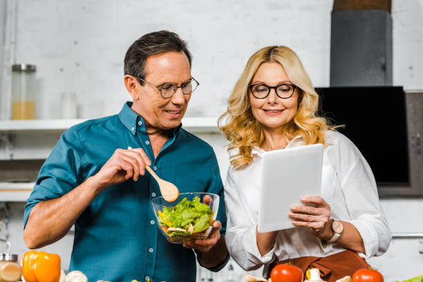 istock mature wife showing something on tablet to husband in kitchen 1094473808