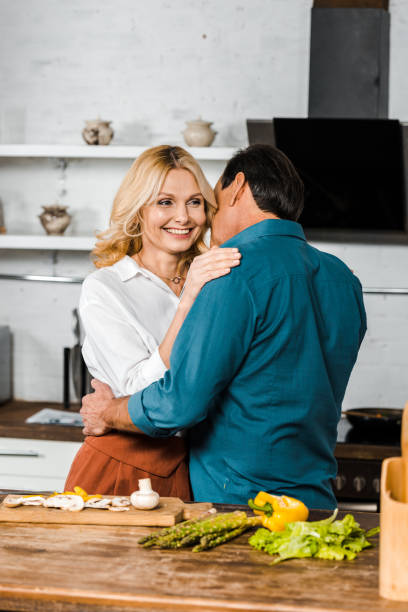 istock happy middle aged wife and husband hugging in kitchen 1094474070