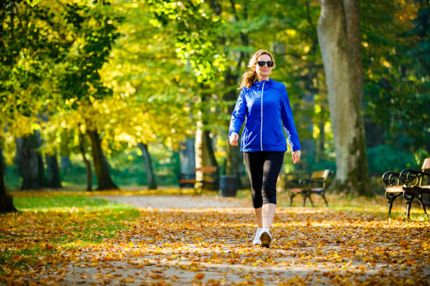 donna di mezza età che corre nel parco cittadino - relaxation exercise foto e immagini stock