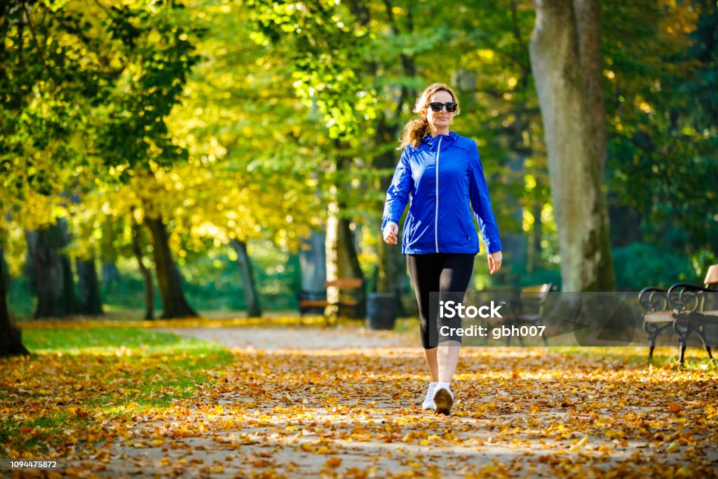 Mid aged woman running in city park Walking Stock Photo