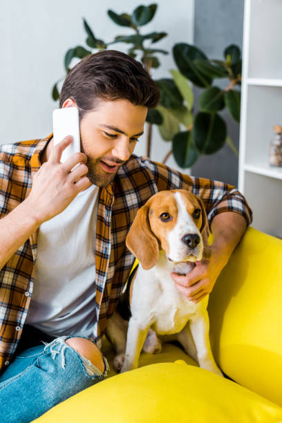 istock handsome man in checkered shirt talking on smartphone and looking at dog 1094476840
