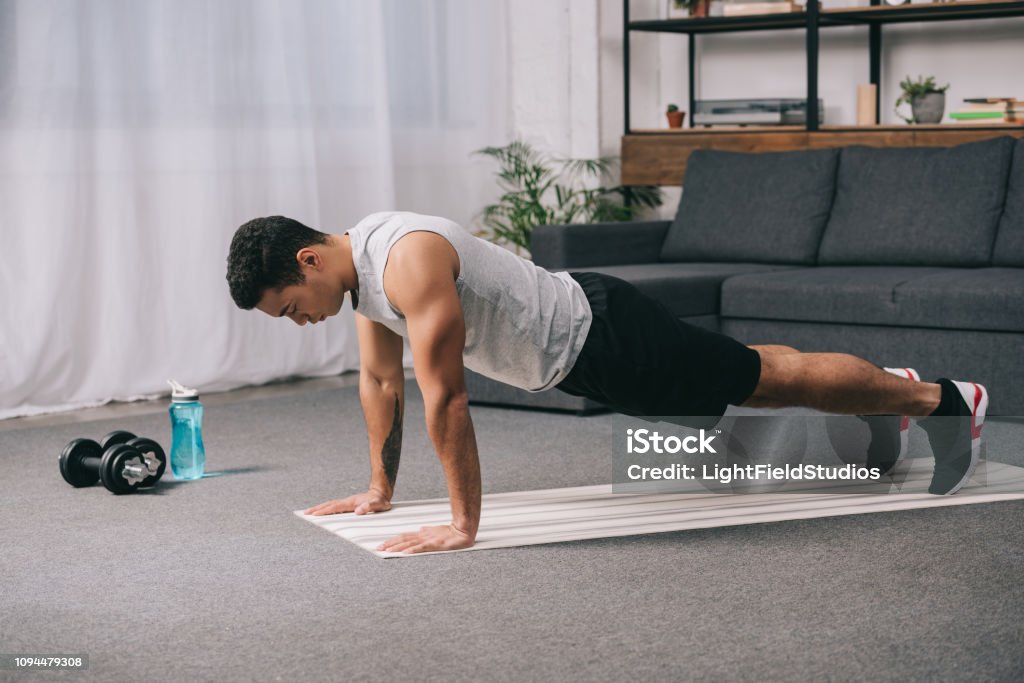 bi-racial man doing push ups in sportswear on  fitness mat Push-ups Stock Photo