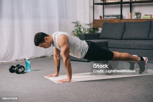 Biracial Man Doing Push Ups In Sportswear On Fitness Mat Stock Photo - Download Image Now