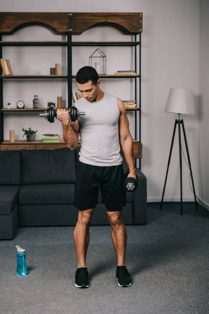istock mixed race man looking at muscles on hand while doing exercise in living room 1094479548