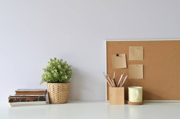 istock Workspace with books, coffee, pencil, plant and sticky note paper on board with office white desk. 1094484414