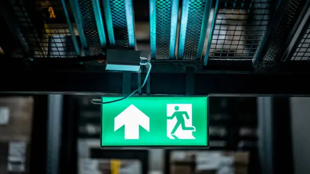 Photo of Green emergency exit sign or fire exit sign showing the way to escape with arrow symbol.