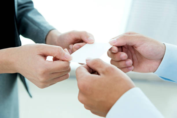 Businesspeople pass a business card