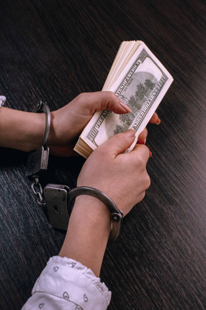 istock hands in handcuffs holding paper money 1094499564