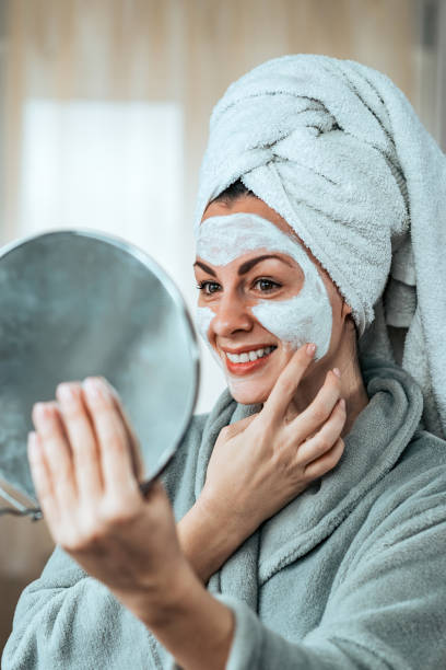 istock Charming woman holding mirror and applying cream after bath. 1094500012