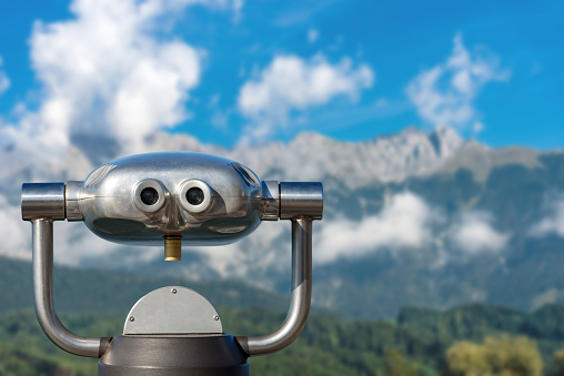 Coin operated electronic binoculars for tourists on a blurred mountain landscape