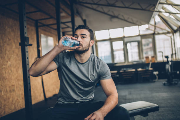 uomo che beve acqua dopo l'allenamento in palestra - drinking men water bottle foto e immagini stock
