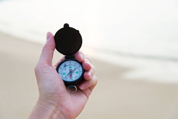 człowiek ręka trzyma kompas na plaży - compass exploration the way forward beach zdjęcia i obrazy z banku zdjęć