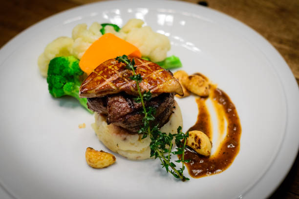 istock Grilled tenderloin filet mignon medallion with bacon mashed potatoes & seasonal vegetables.  Topped with foie gras and served with red wine garlic confit sauce. 1094512100