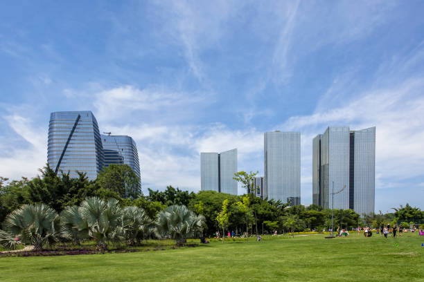 Lawn in the park with skyline of modern buildings and mirrored on sunny day with sparse clouds stock photo