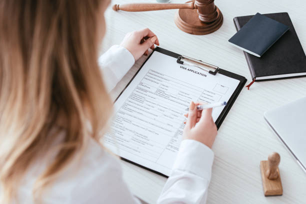 istock selective focus of woman holding pen near document with visa application lettering 1094519302