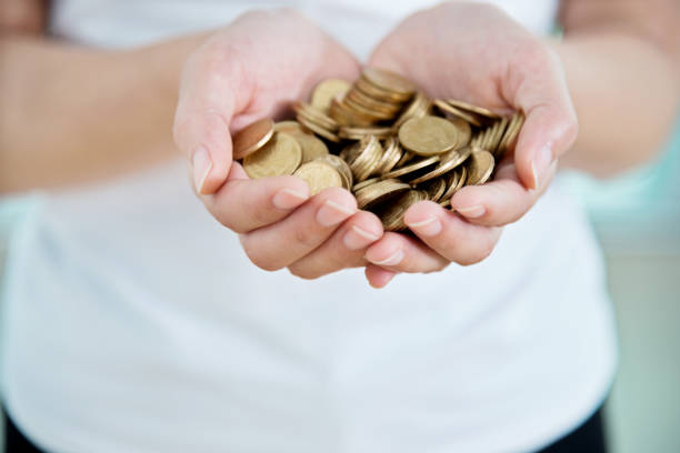 Hands holding a golden coin with a dollar sign, symbolizing wealth and financial growth.