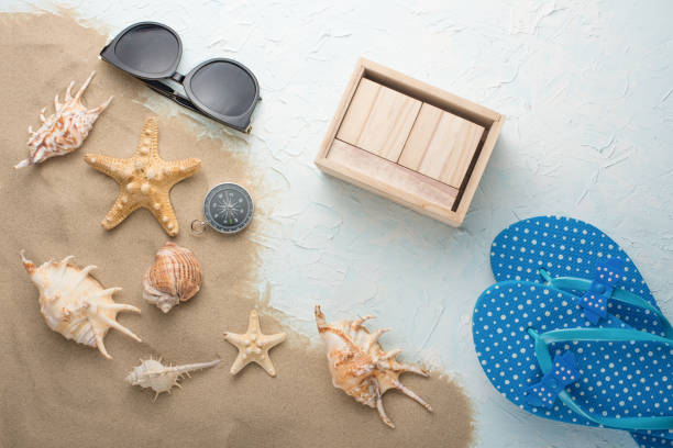 istock Shells in the sand on the blue textures with sunglasses and beach slippers, with an empty calendar 1094520928