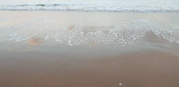 istock White sea foam in surf arriving on sandy beach 1094521774