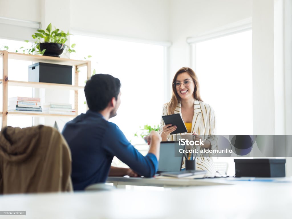 Hispanic woman and man working in and office Hispanic woman and man working in and office as team sharing information 20-29 Years Stock Photo