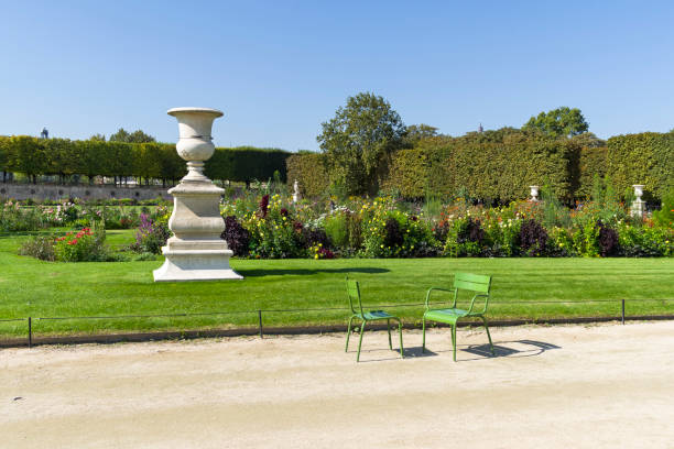 Outdoors metal chairs typical for Tuileries and Luxembourg gardens in Paris, France. Focus on chairs, blurred crowd on the background