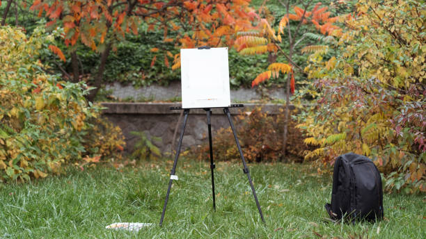 istock Easel, black backpack and paints are standing on the grass in the autumn park 1094525752