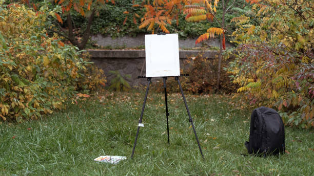 istock Easel, black backpack and paints are standing on the grass in the autumn park 1094525764