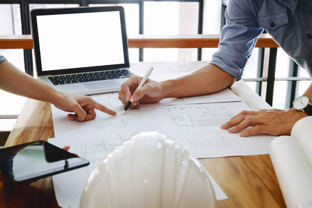 istock Close up of engineer hands discussing a building construction project with blank screen laptop at workplace 1094530544