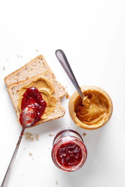 Peanut butter jar, fruit jam and toast isolated on a white background viewed from above. Top view Peanut butter jar, fruit jam and toast isolated on a white background viewed from above. Top view peanut butter and jelly sandwich stock pictures, royalty-free photos & images