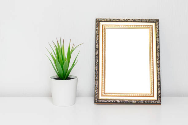 istock Minimalistic interior design with photo frame and a plant in white pot on a desk 1094544460